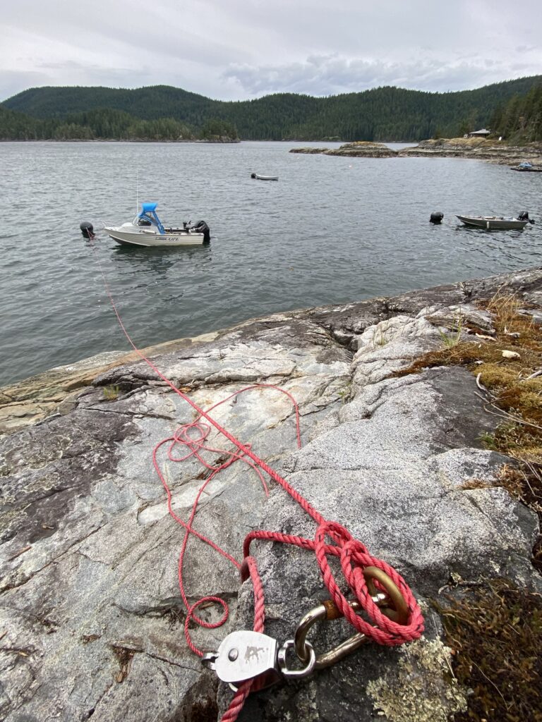 Photo of an eye boat, carabiner and pulley with pink rope strung through it and also looped up over the eye bolt and a boat in the distance tied to the rope by a buoy.